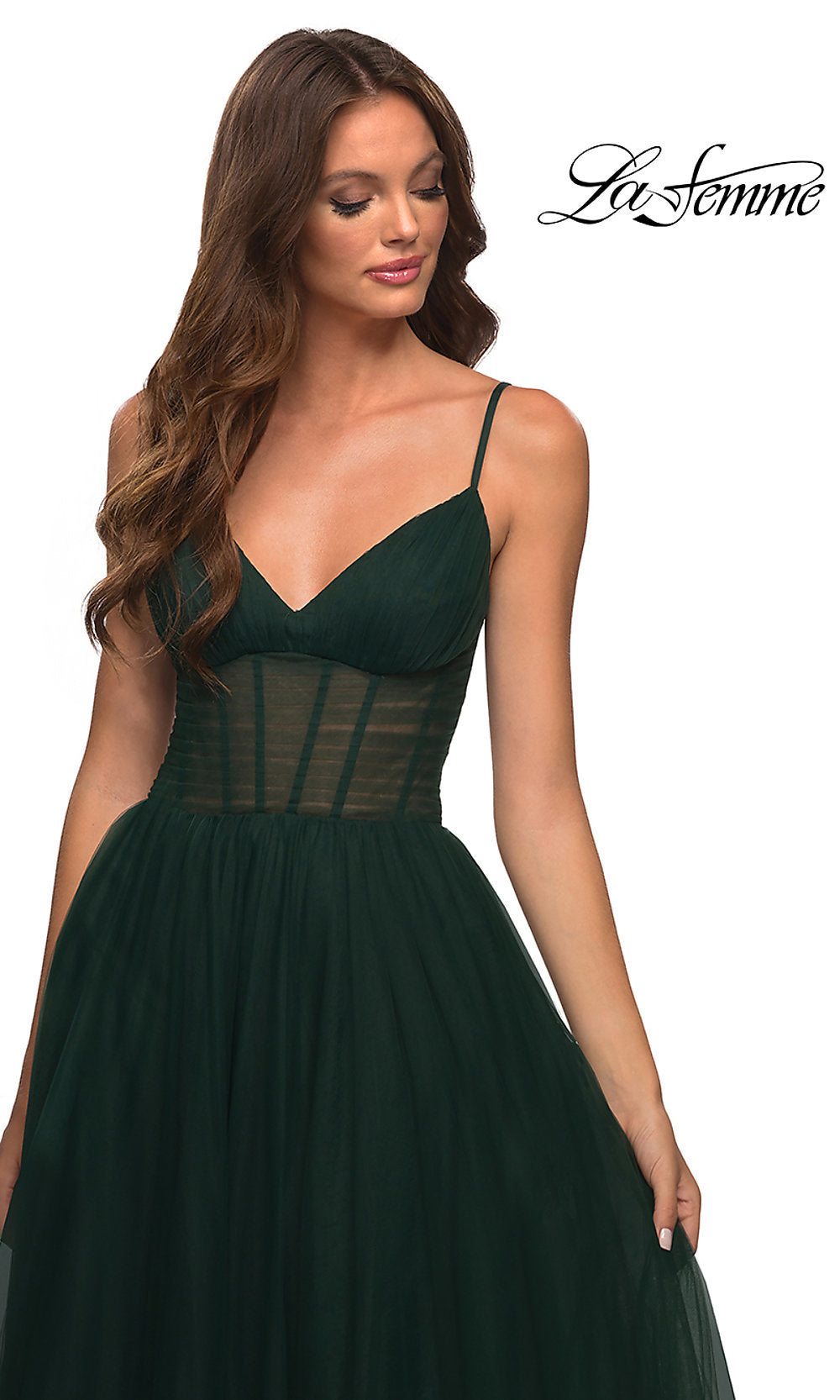 A woman in a Long La Femme Prom Dress with a sheer corset waist holds the skirt. The